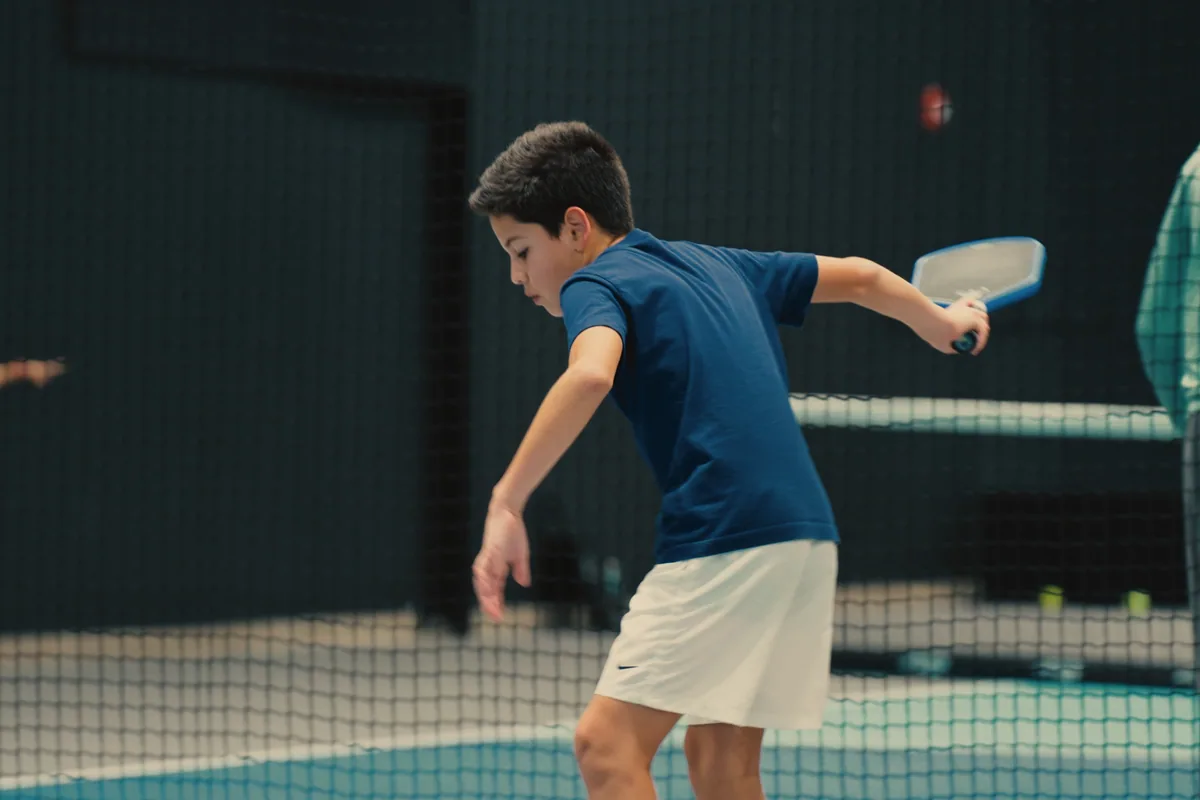 Junior player tracking a shot during pickleball practice.
