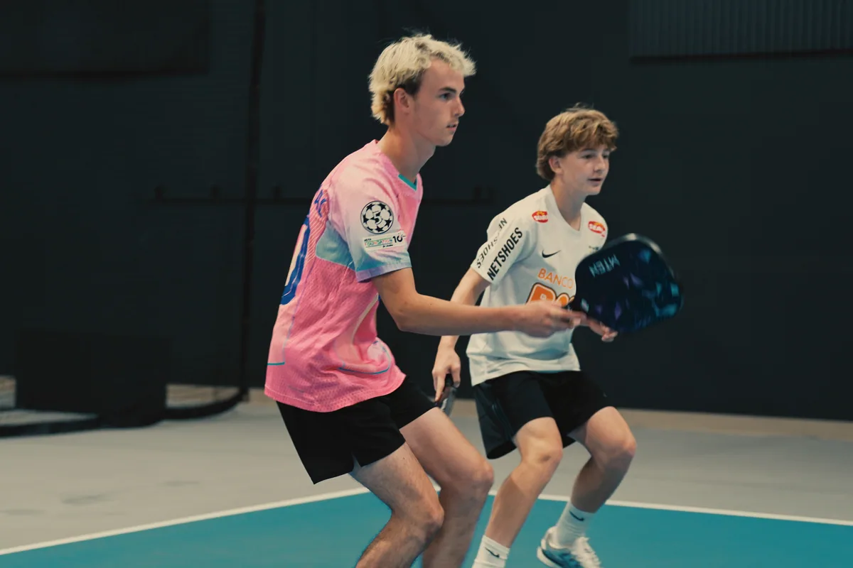 Two junior players moving together during coached court play.