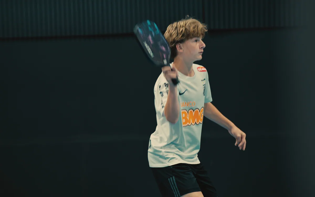 Junior player in motion during an indoor pickleball match.
